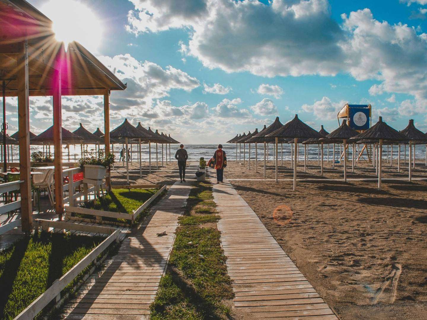 famiglia in spiaggia con ombrelloni e passerella fino al mare